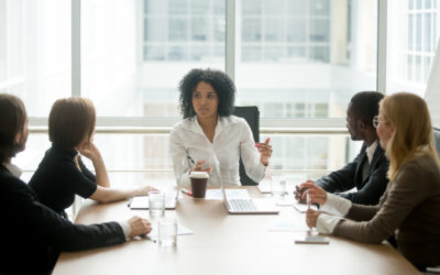 Black female boss leading corporate meeting talking to diverse businesspeople