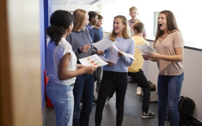 Excited Teenage High School Students Celebrating Exam Results In School Corridor